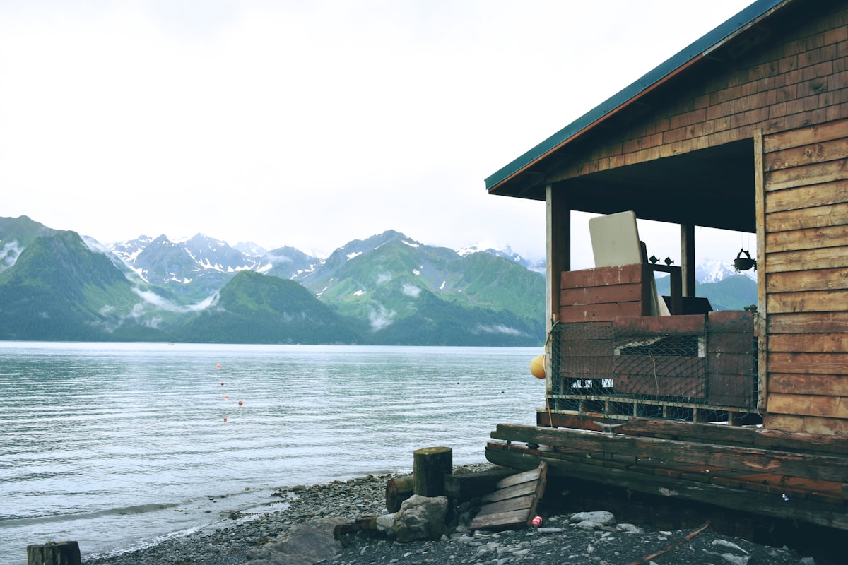 Cabane en bois face aux montagnes verdoyantes d'Alaska