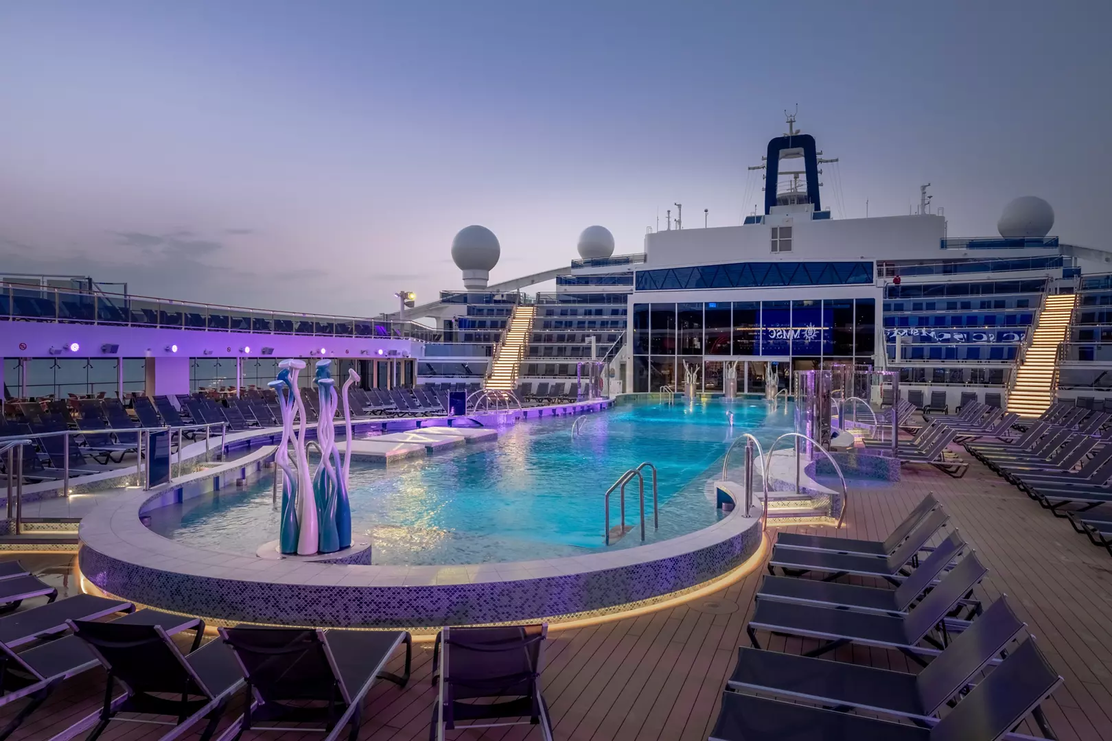 Zone piscine La Plage sur le MSC World America au crépuscule avec terrasses et transats